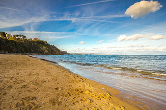 Sandy Beach Shoreline with Blue Sky and Coastal Cliffs