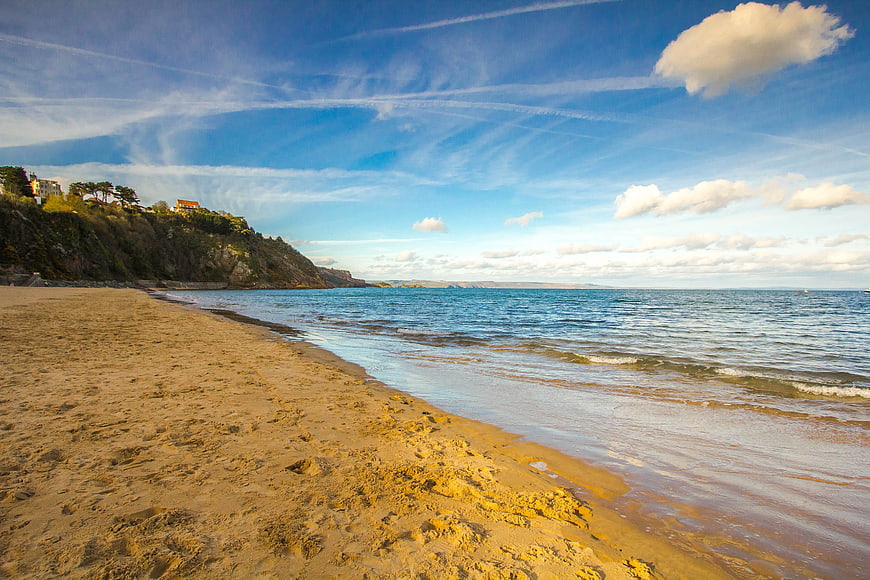 Sandy Beach Shoreline with Blue Sky and Coastal Cliffs