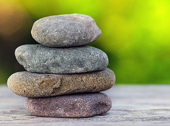 Stacked Zen Stones On Wooden Surface With Green Background