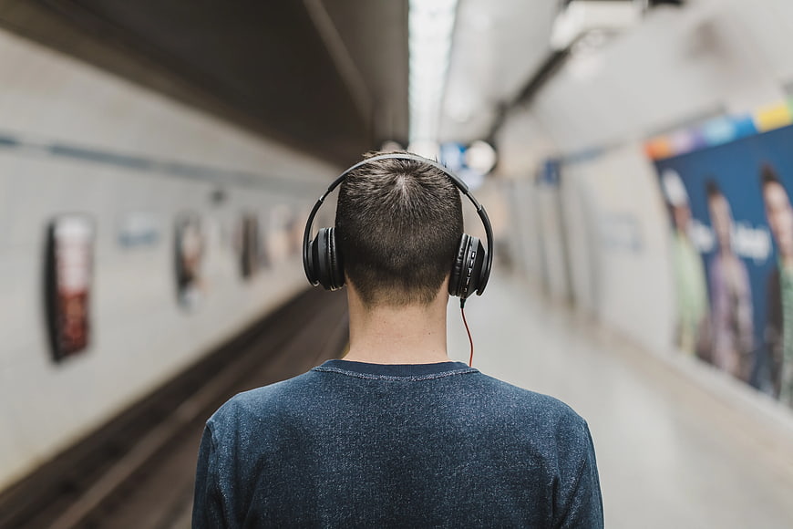 Man with headphones waiting at subway station platform