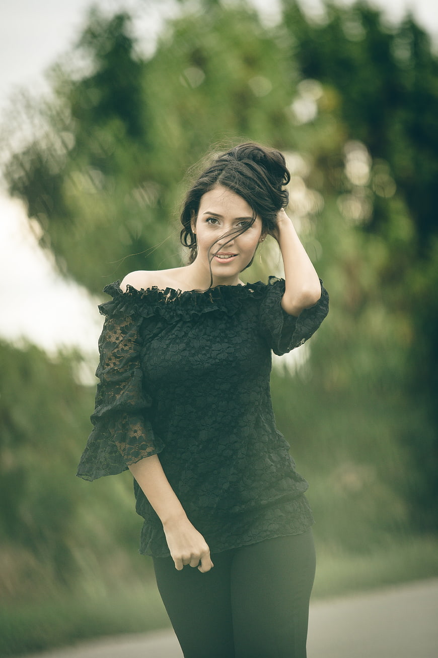 Young woman in black lace top posing outdoors