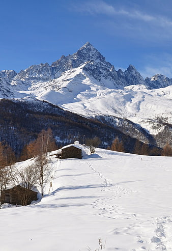 Snowy Mountain Landscape with Stone Cabin and Footprints