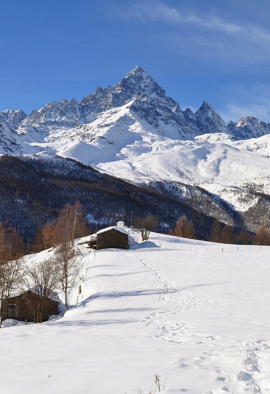 Snowy Mountain Landscape with Stone Cabin and Footprints