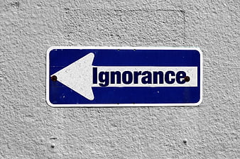 Blue street sign pointing left with word ignorance