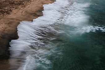 Aerial View of Ocean Waves Crashing on Sandy Beach