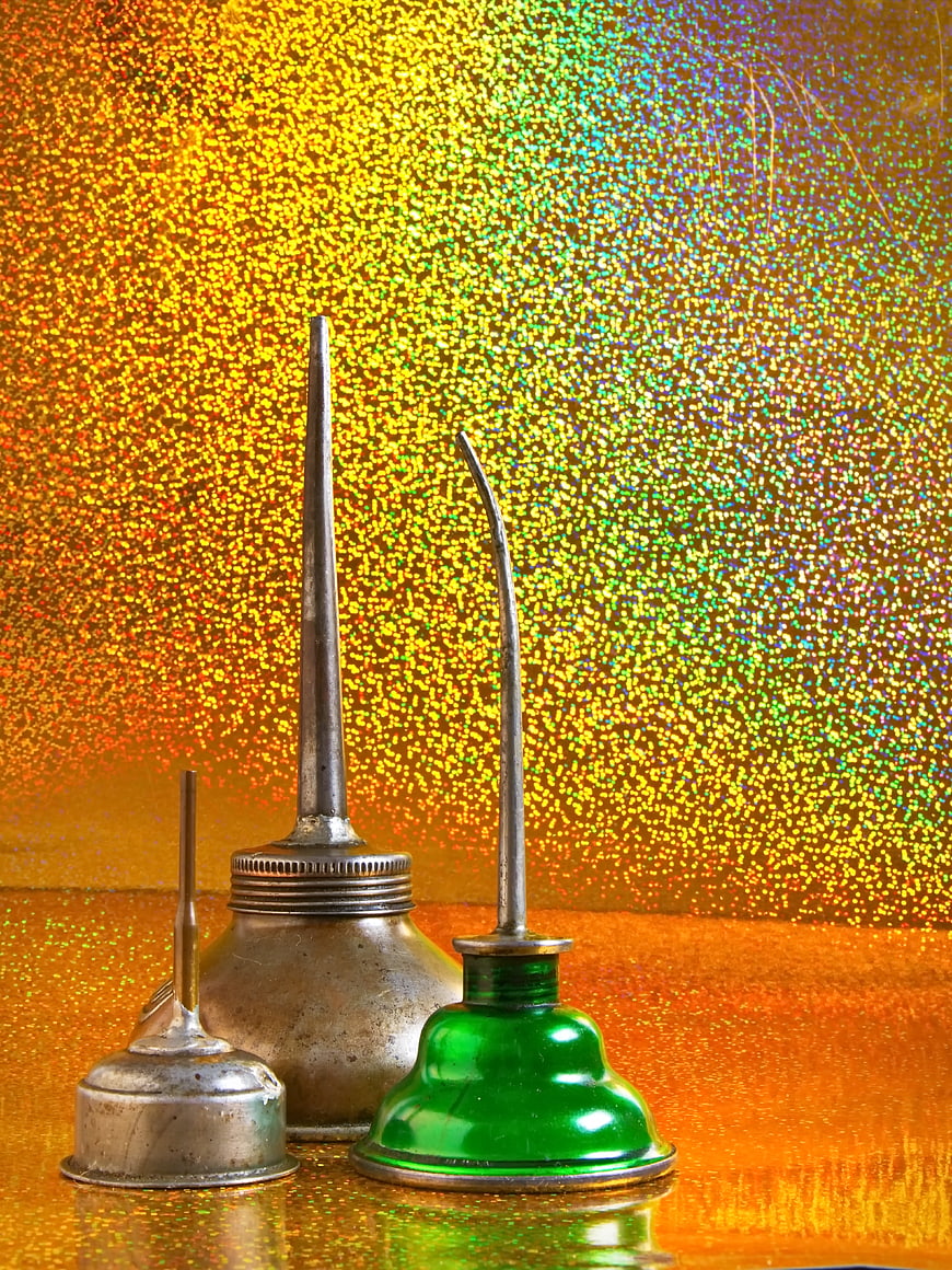 Vintage metal oil cans on glittering gold background