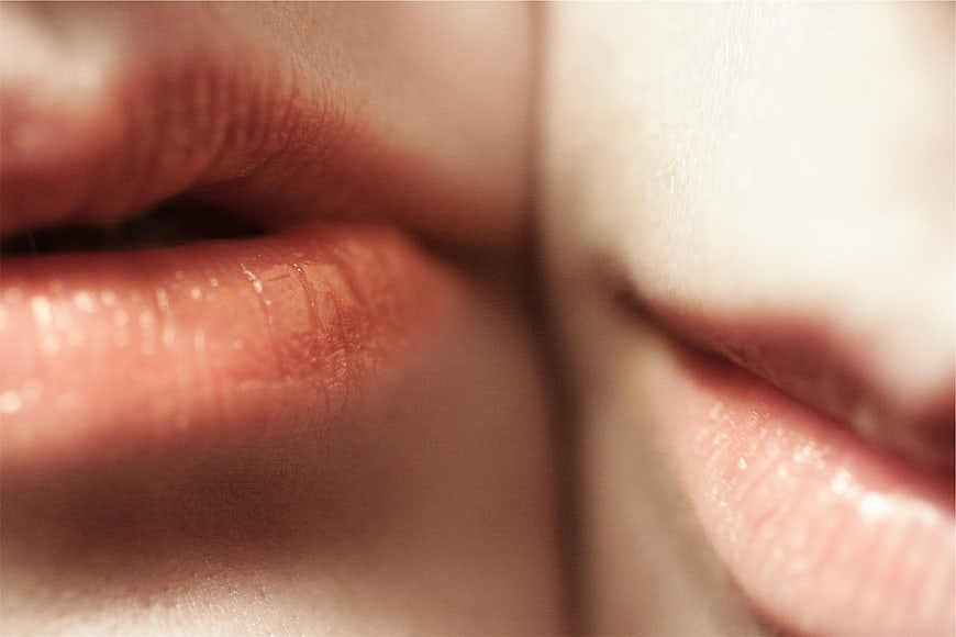 Close-up of two pairs of lips kissing intimately