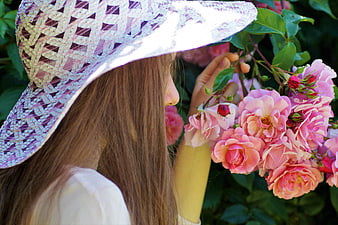 Young Woman in Lace Hat Smelling Pink Roses in Garden