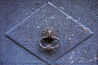 Close-up of rusty antique door knocker on weathered wooden door