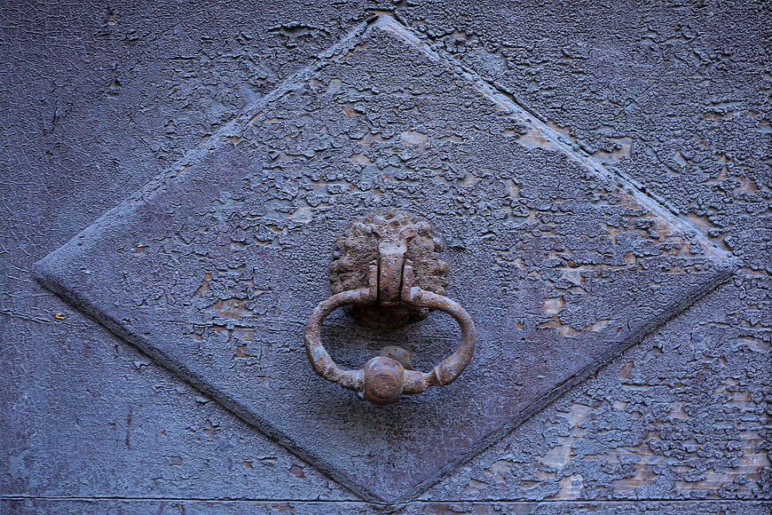 Close-up of rusty antique door knocker on weathered wooden door