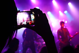 Silhouette of person recording live concert on smartphone