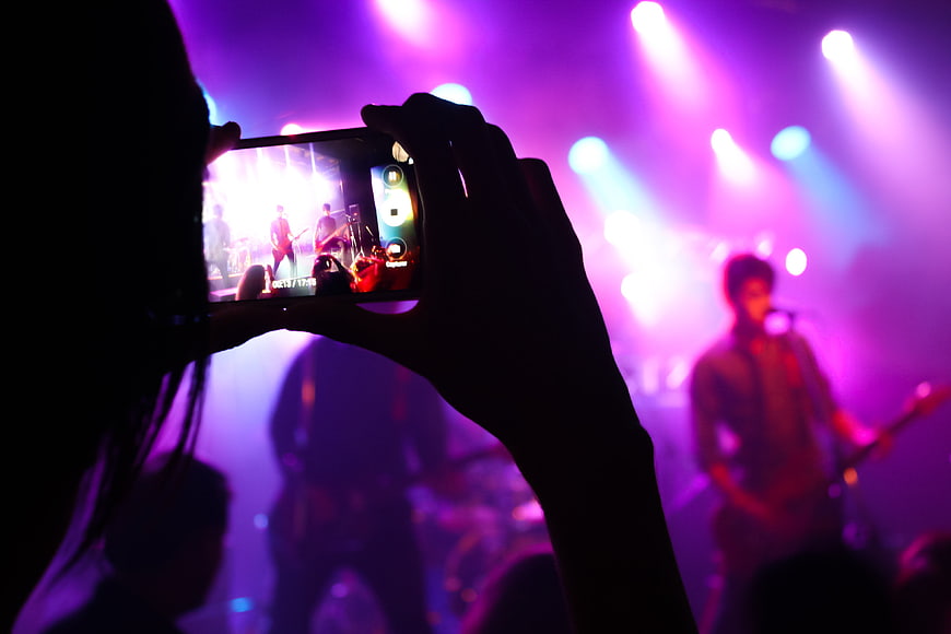 Silhouette of person recording live concert on smartphone