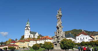 Baroque plague column and church tower in European town square