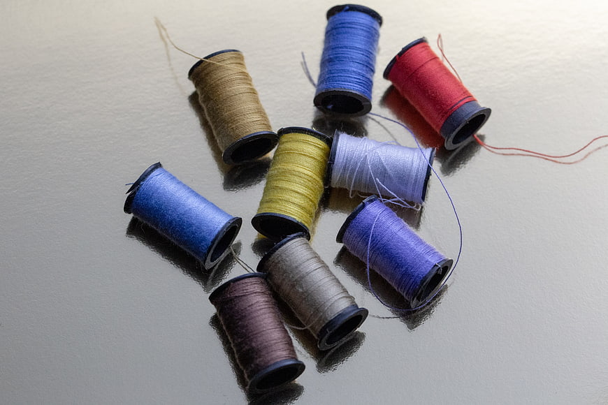 Colorful Sewing Thread Spools on Reflective Surface