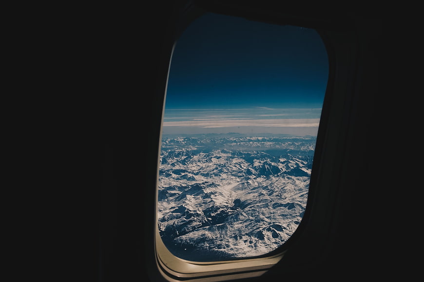 Snowy mountain range view from airplane window