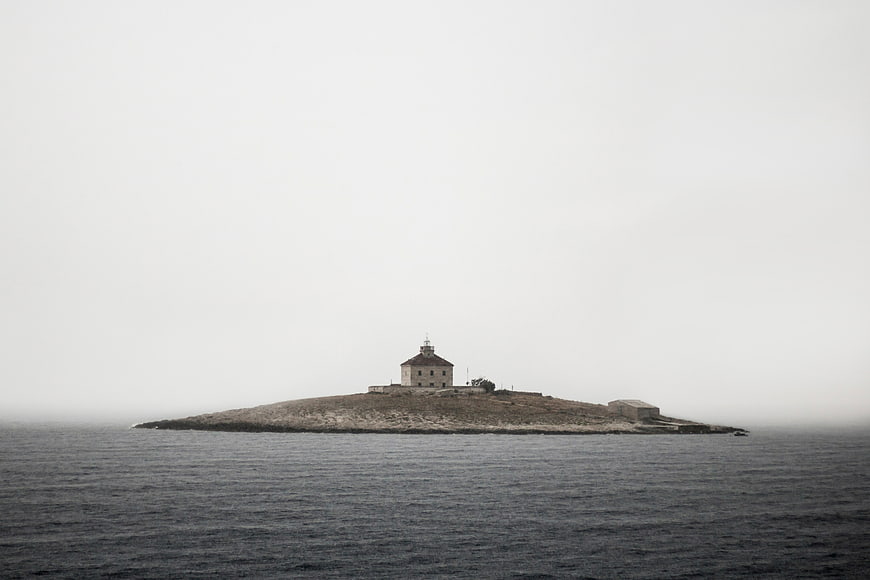 Lighthouse on small island in foggy sea
