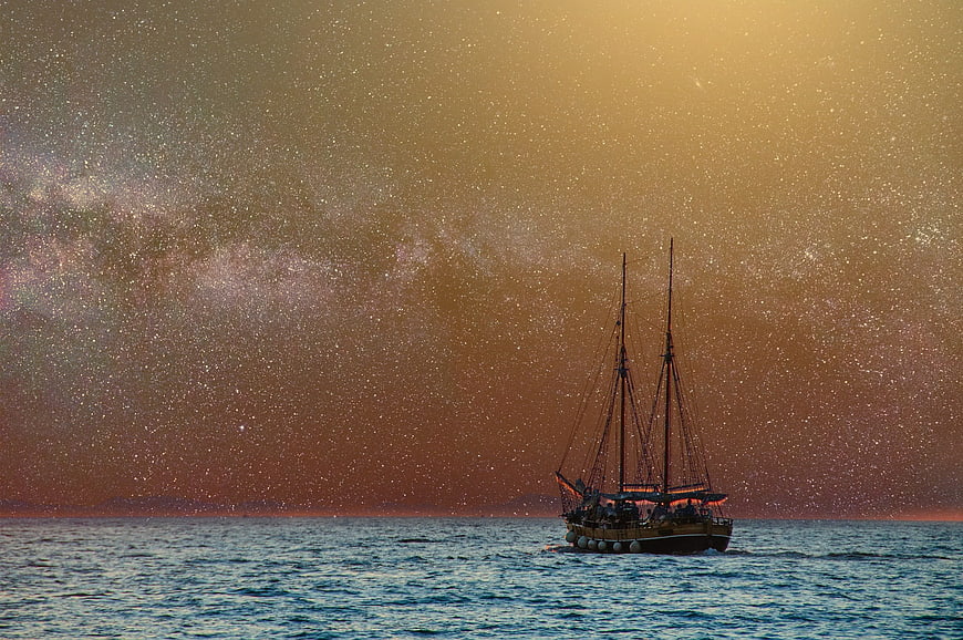 Sailboat on Ocean Under Starry Night Sky