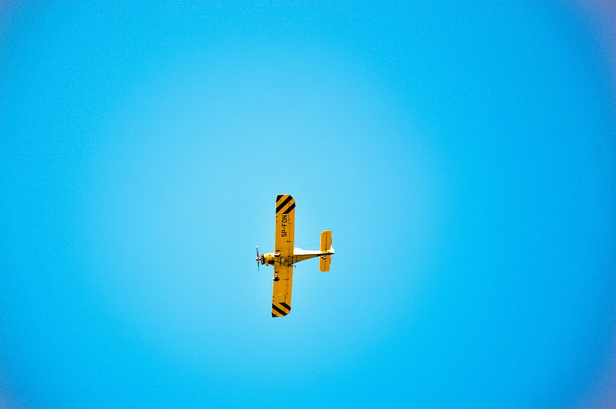 Yellow biplane flying against a clear blue sky