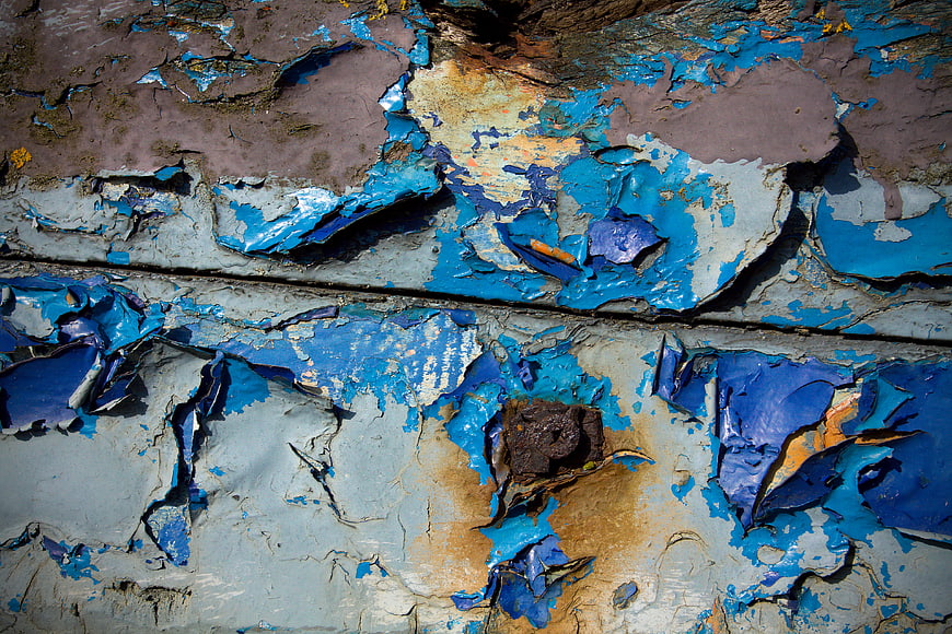 Close-up of peeling blue paint on weathered wood texture