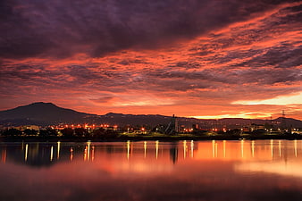 Dramatic Sunset Sky Over Water with City Lights Reflection