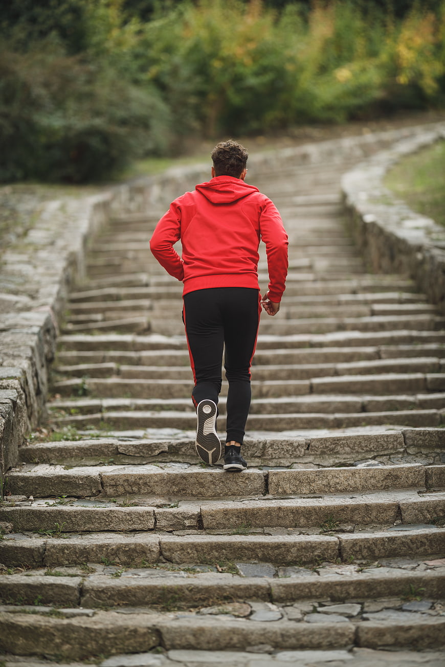 Man Running Up Stone Stairs in Red Hoodie