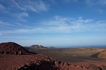 Vast volcanic landscape with red soil and blue sky