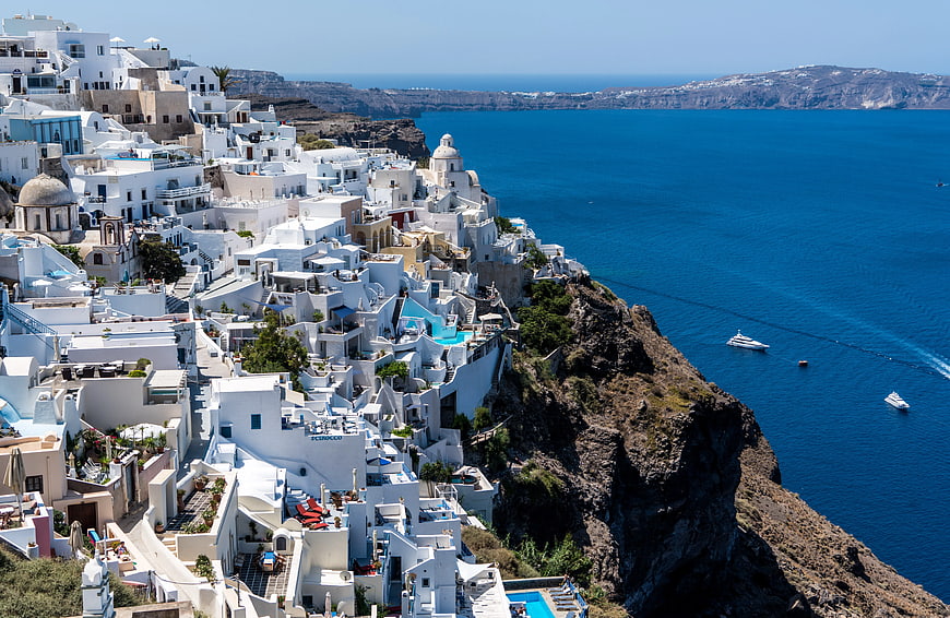 White buildings on Santorini cliff overlooking blue Aegean Sea