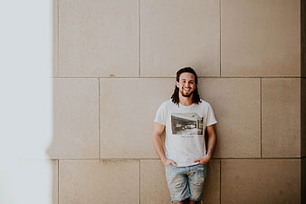 Happy Man with Dreadlocks Leaning Against Beige Wall