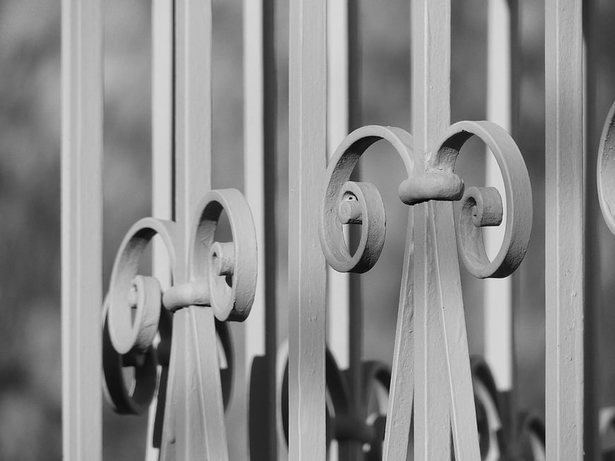 Close-up of vintage wrought iron fence scrollwork in black and white