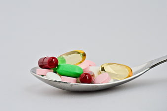 Assorted Colorful Pills And Capsules On A Silver Spoon