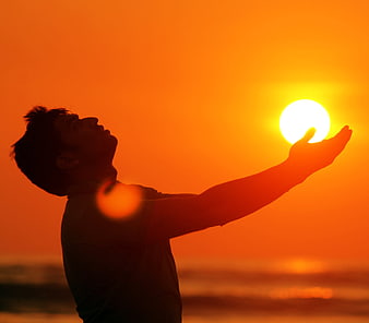 Silhouette of Man Holding Sun at Sunset