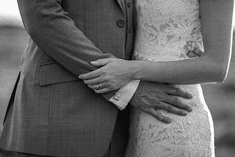 Black and white close-up of bride and groom holding hands