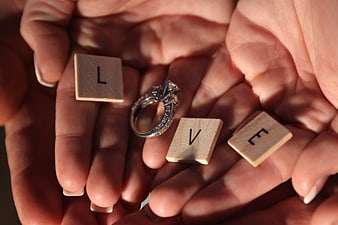 Diamond ring and wooden LOVE letter tiles held in cupped hands