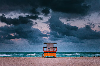 Orange Lifeguard Tower on Sandy Beach Under Stormy Sky
