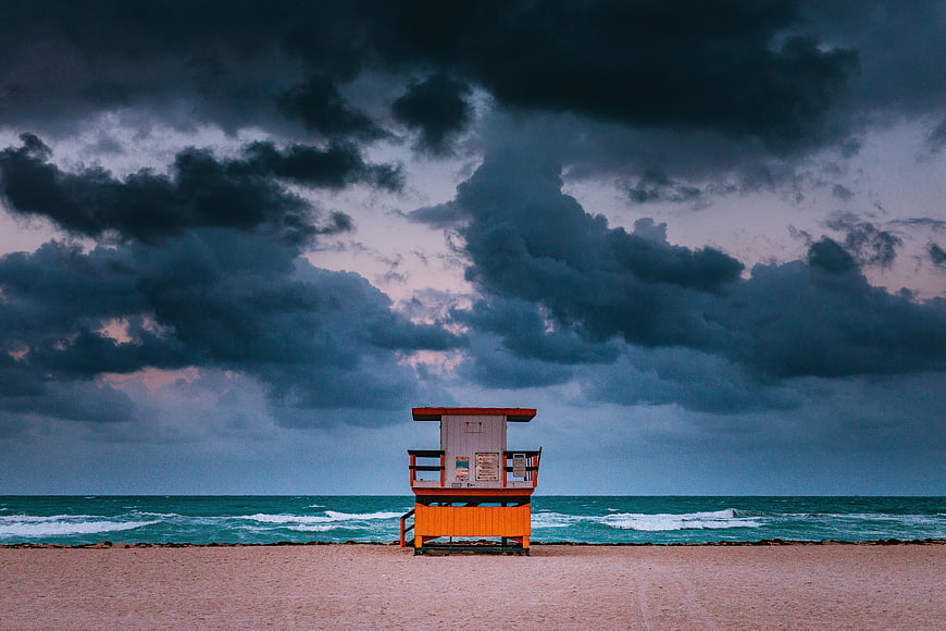 Orange Lifeguard Tower on Sandy Beach Under Stormy Sky