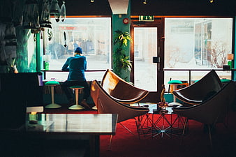 Woman in Blue Beanie Sitting by Window in Retro Cafe