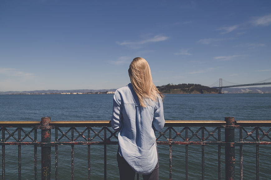 Woman in Denim Looking at Bay Bridge from Pier