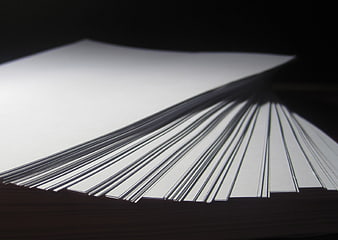 Stack of white paper sheets fanned out on dark background