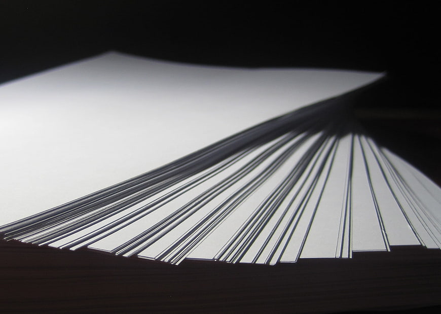 Stack of white paper sheets fanned out on dark background