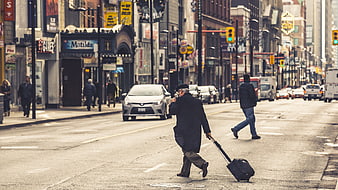 Senior man with suitcase crossing busy city street