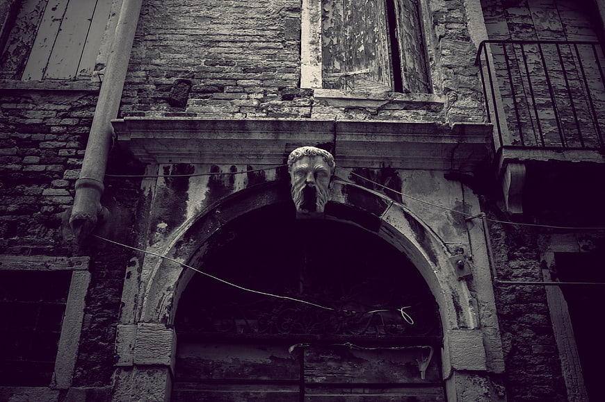 Gothic Stone Mask Sculpture On Weathered Italian Building Facade