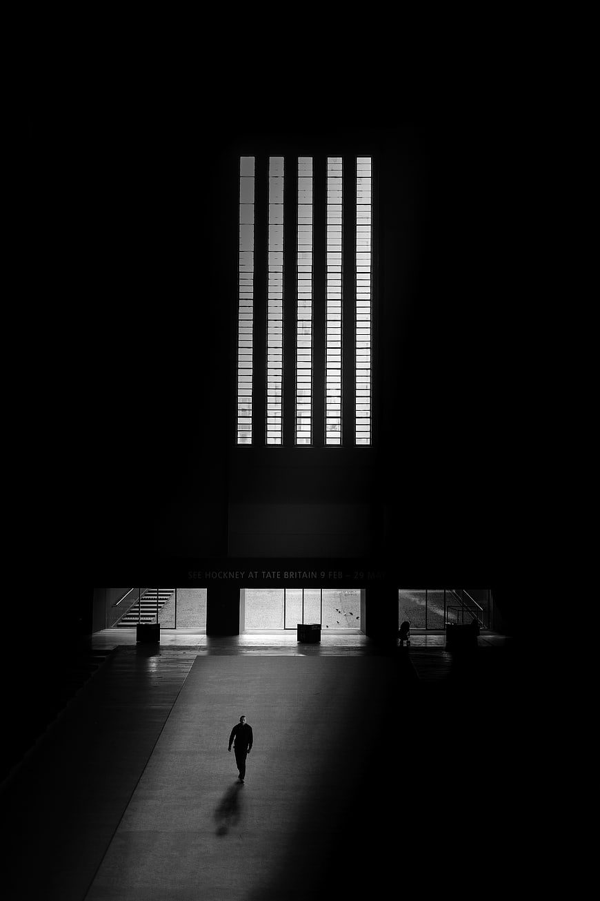 Silhouette of Man Walking in Dark Museum Hall