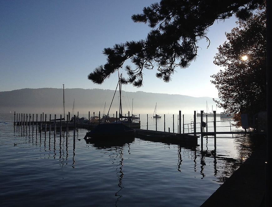 Silhouetted boats in misty harbor at sunrise
