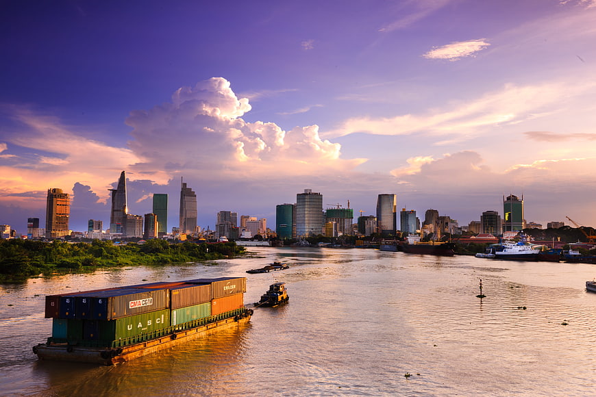 Cargo Barge on Saigon River with Ho Chi Minh City Skyline at Sunset