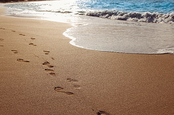 Footprints in sand on tropical beach with ocean waves