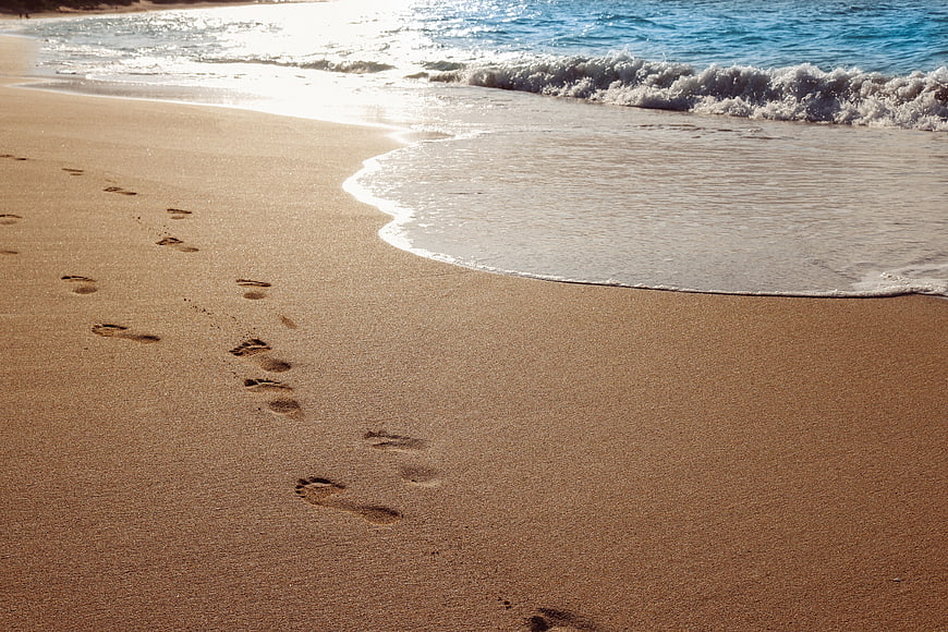 Footprints in sand on tropical beach with ocean waves