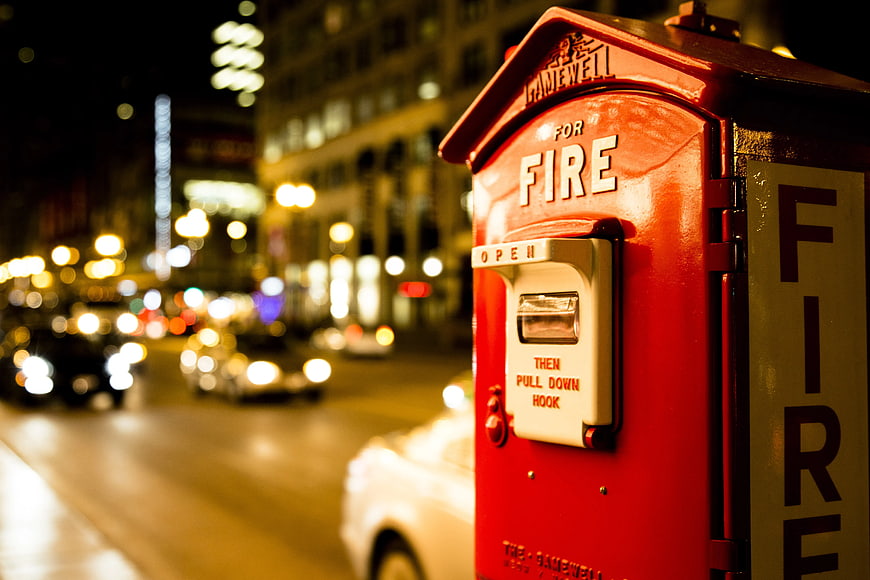 Red Fire Alarm Box on City Street at Night