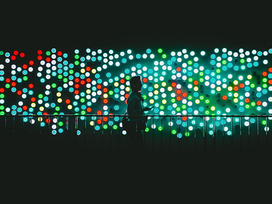 Silhouette of person against colorful bokeh lights at night