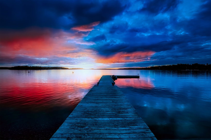 Dramatic Sunset Over Wooden Dock on Calm Lake