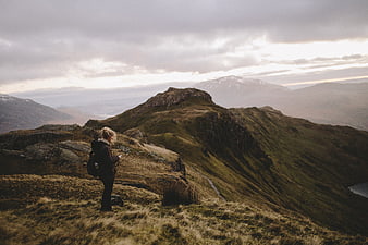 Woman hiker standing on mountain ridge overlooking vast landscape